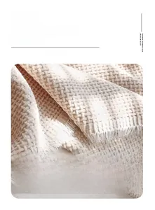 Detail of beige chenille sofa cover showing thick waffle weave and elegant tassel edges