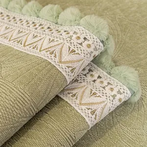 Copridivano in ciniglia verde con pizzo bianco e pompon decorativi in peluche