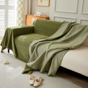 Green chenille sofa cover with herringbone texture and fringe displayed on a couch