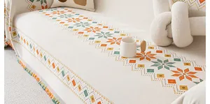 Detail of bohemian chenille sofa cover with orange geometric patterns and fringes