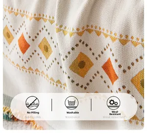 Detail of bohemian chenille sofa cover with woven geometric patterns and colorful tassels