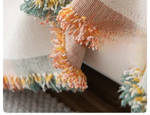 Detail of bohemian chenille sofa cover showing geometric weave and two-tone tassels