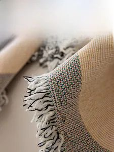 Macro detail of Nordic knit sofa cover showing multi-colored weave and fringe edges
