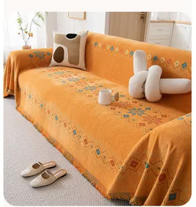 Detail of bohemian chenille sofa cover with orange geometric patterns and fringes