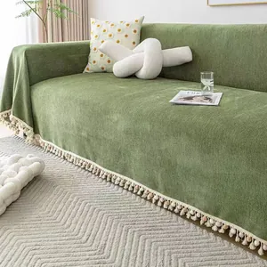 Detail of green herringbone chenille sofa cover with decorative colorful pom-pom fringe