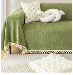 Close-up of grass green chenille sofa cover with herringbone weave and colorful tassels