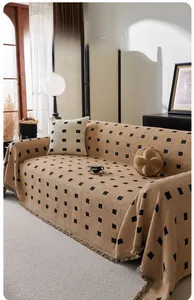 Close-up of thick knitted chenille sofa cover with black dots and tassel fringes