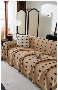 Detail of warm brown boucle yarn sofa cover with black geometric squares and fringes