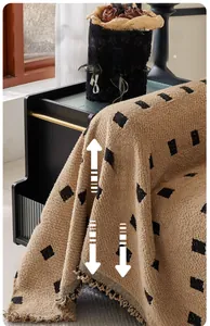 Detail of camel chunky knit sofa throw with black diamond patterns and fringe edges