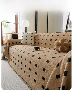 Close-up of brown textured sofa throw with black geometric squares and fringe detail