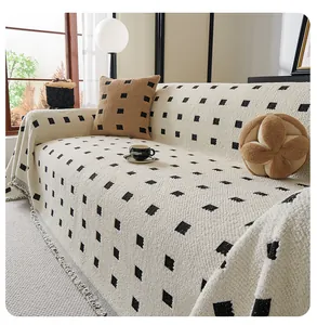 Close-up of thick chenille sofa cover with black geometric patterns and fringe edges