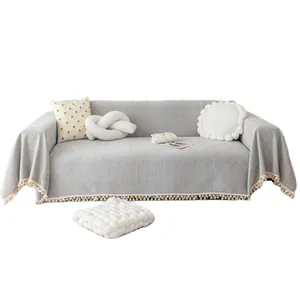 Minimalist light gray herringbone chenille sofa cover with pom-pom fringe and throw pillows