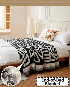 Détail du chemin de lit en chenille noir et blanc avec des franges et motifs géométriques