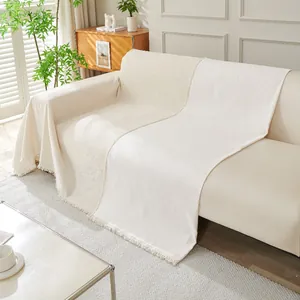 Funda de sofá de chenilla lisa con flecos decorativos en un salón de estilo moderno