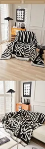 Détail d'un jeté de fauteuil chenille géométrique noir et blanc avec des franges