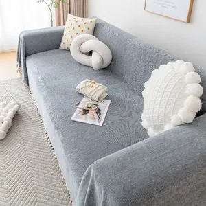 Classic dark grey herringbone chenille sofa cover with pom-pom fringe in a cozy living room
