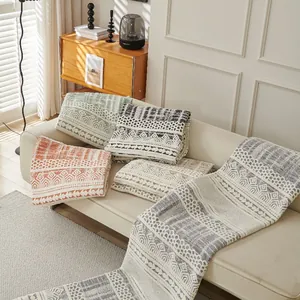 Bohemian geometric knit sofa cover with fringe detail in cozy living room setting