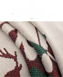 Macro detail of quilted chenille Christmas sofa cover featuring red and green reindeer pattern