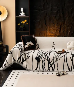 Close-up of chenille sofa throw with black branch patterns and decorative fringe edges
