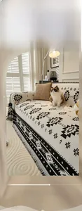Detail of bohemian chenille sofa cover with black and white geometric patterns and tassels