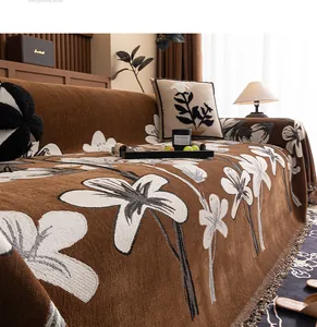 Detail of brown chenille sofa cover with large white floral patterns and tassel edges