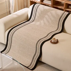 Chenille herringbone sofa cover with black piping and minimalist fringe on a couch