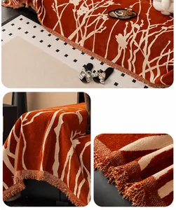 Detail of orange chenille sofa cover featuring white dried branch patterns and fringe edges