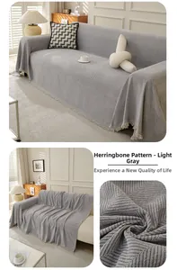 Close-up of light gray herringbone knit sofa cover featuring detailed fringe tassels