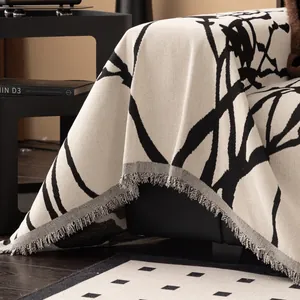 Copridivano minimalista in ciniglia con linee astratte nere ed eleganti frange