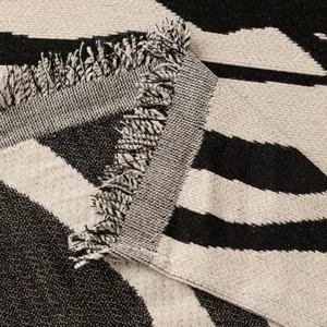 Copridivano in ciniglia bianco e nero con strisce geometriche e nappe decorative