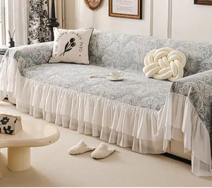Detail of light blue chenille sofa cover with floral palm patterns and white ruffle hem