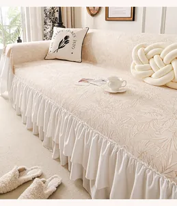 Detail of beige chenille sofa cover showing jacquard leaf texture and ruffled hem