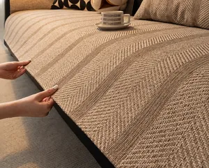 Close-up of beige herringbone linen sofa cover fabric texture shown under warm lighting