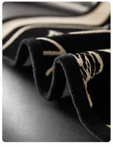Dettaglio del cuscino in ciniglia con bordi neri a onde e ricamo jacquard in bianco