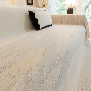 Primer plano de funda de sofá de chenilla beige con textura ondulada y flecos crema