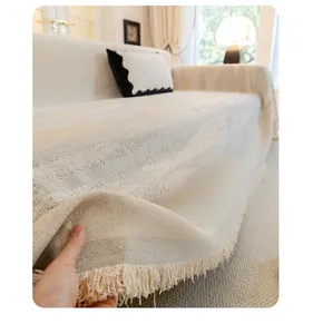 Detalle de la textura de tela de chenilla gruesa y flecos de la funda de sofá beige