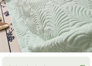 Detailed close-up of light green quilted sofa cover with elegant leaf pattern texture