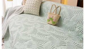 Detail of light green sofa cover with embossed leaf pattern texture in a home setting