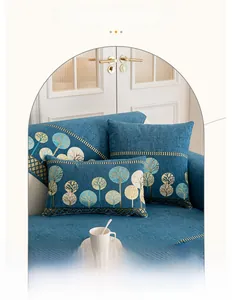 Détail du coussin de canapé en chenille bleu foncé avec broderie de forêt dorée