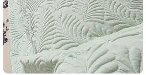 Detail of mint green sofa cover showing feather quilted texture and premium fabric density