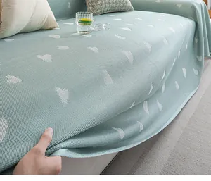Close-up of mint green knitted cooling sofa cover with white heart jacquard texture