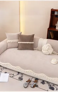Detail of chenille sofa cover with fringe, textured beige fabric, and anti-slip backing