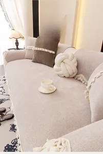 Detailed texture of beige chenille sofa cover with decorative tassels and a knot pillow