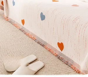 Detail of cream chenille sofa cover with orange heart jacquard and colorful fringe