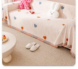 Detail of cream chenille sofa cover with colorful hearts and decorative fringe texture