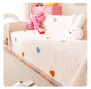 Detail of cream chenille sofa cover showing colorful heart patterns and fringe edges
