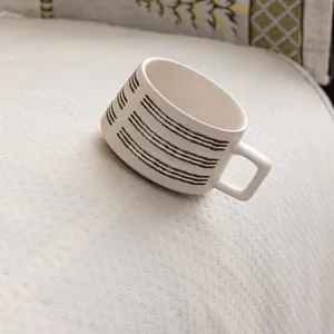 Modern cream ceramic coffee mug with speckled finish and unique square handle