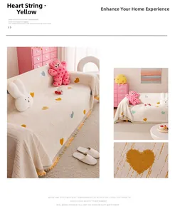 Detail of chenille sofa cover with yellow heart jacquard pattern and fringe edges
