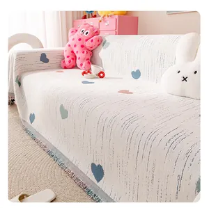 Close-up of cream chenille sofa cover with heart patterns and decorative fringe details