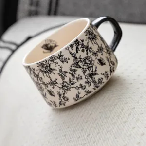 Vintage floral ceramic coffee mug with black butterfly patterns and round handle